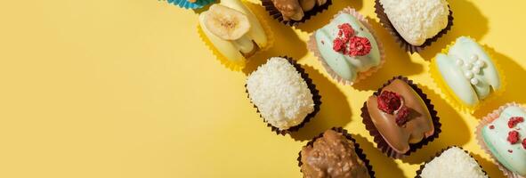 Banner with different macaroons on yellow background top view, flat lay. Copy space. photo
