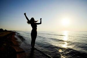 Silhouette of a girl against the sunset by the sea photo