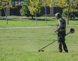 Worker mowing the lawn. Mowing grass trimmer photo