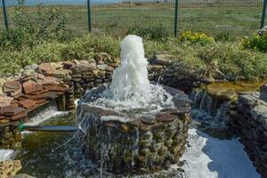 Small fountain in the flower bed area photo