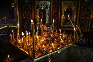 Burning candles on a stand near the icons in the chapel. photo