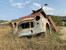 Broken and rusty car was parked in an empty lot for a long time so it was overgrown with grass photo