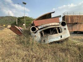 roto y oxidado coche estaba estacionado en un vacío lote para un largo hora entonces eso estaba descuidado con césped foto