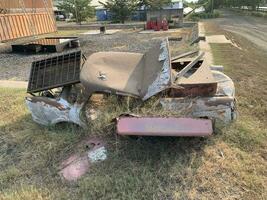 Broken and rusty car was parked in an empty lot for a long time so it was overgrown with grass photo