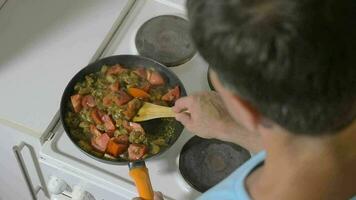 Man stewing tomatoes, mushrooms and potatoes in pan video