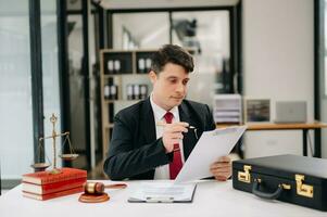 justice and law concept. Male judge in a courtroom  the gavel, working with smart phone and laptop and digital tablet computer on wood table photo