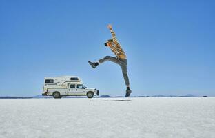 Bolivia, Salar de Uyuni, boy jumping at camper on salt lake photo