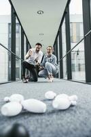 Cheering businessman and businessman in office passageway with fallen pins photo