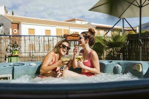 Two happy women having a drink in a hot tub photo