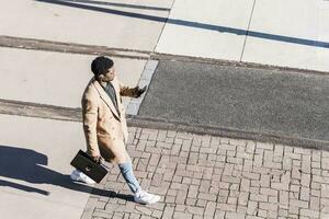 empresario caminando al aire libre con maletín, célula teléfono y auriculares foto