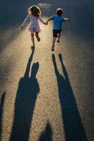 Rear view of siblings holding hands and running on road photo