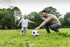 Happy father playing football with son in a park photo