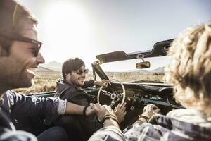 Happy friends in convertible car on a road trip photo