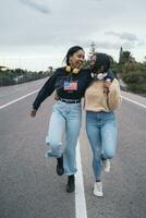 Two happy young women walking on a road photo