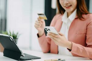 Woman using smart phone for mobile payments online shopping, omni channel, sitting on table, virtual icons graphics interface screen photo