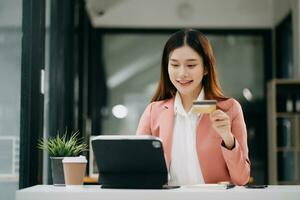Asian Woman using smart phone for mobile payments online shopping,omni channel,sitting on table,virtual icons graphics interface screen photo