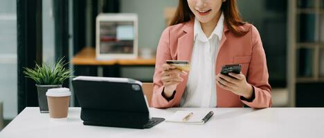 Woman using smart phone for mobile payments online shopping, omni channel, sitting on table, virtual icons graphics interface screen photo