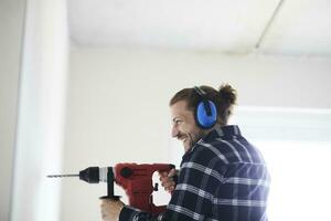 Happy worker using electric drill on a construction site photo