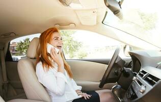 Happy business woman using her smartphone in a car photo