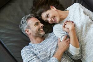 Happy couple lying on couch at home photo