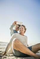 padre teniendo divertido con su hijo en el playa, tomando teléfono inteligente imágenes foto