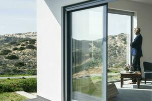 Senior businessman standing at panorama window looking out photo