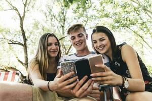 Three happy friends looking at cell phones outdoors photo