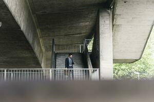 Businessman at underpass checking cell phone photo