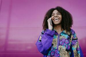 Smiling woman talking on the phone, pink wall in the background photo