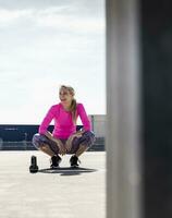 Woman training with dumbells, kneeling on ground photo