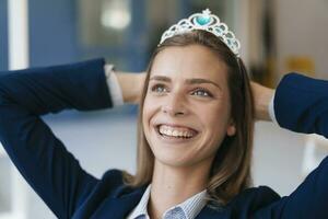 ambicioso joven mujer vistiendo corona como un premio para su logros foto