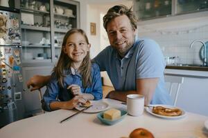 retrato de padre y hija a hogar sentado a desayuno mesa foto