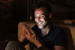 Portrait of happy mature man using cell phone at home photo