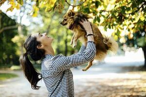 contento joven mujer participación perro en un parque foto