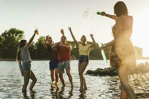 grupo de contento amigos en un río a puesta de sol foto