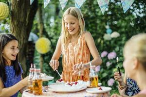 niña sirviendo arriba pastel en un cumpleaños fiesta al aire libre foto