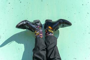 Feet of businessman wearing colorful socks against green wall photo