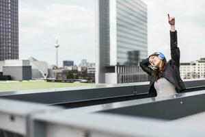 Young woman in the city wearing headphones, dancing photo