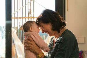 Grandmother holding baby girl, head on head and smiling photo