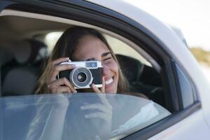 mujer sentado en auto, tomando imágenes con un cámara foto