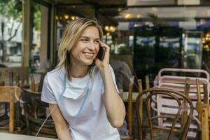 Portrait of woman on the phone with protective mask in front of a closed coffee shop photo