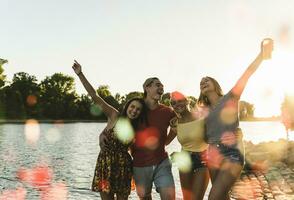 grupo de contento amigos teniendo divertido en un río a puesta de sol foto