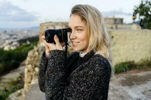 Young woman taking pictures above the city at sunrise, Barcelona, Spain photo