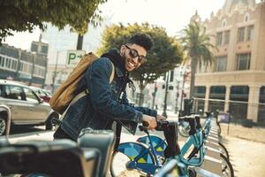 Stylish young man on the street with rental bike photo