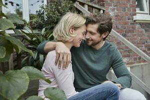 Happy couple sitting on stairs cuddling photo