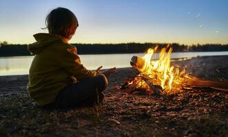 argentina, Patagonia, concordia, chico sentado a acampar fuego a un lago foto
