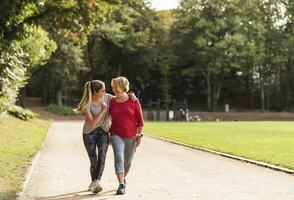 Granddaughter and grandmother having fun, jogging together in the park photo