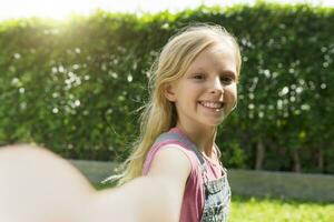 Cute blonde girl taking selfie in garden photo