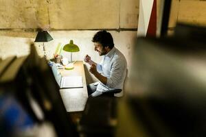 Cheering businessman using laptop on table in the dark photo