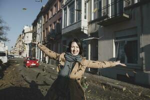 Belgium, Brussels, portrait of happy woman throwing autumn leaves in the air photo